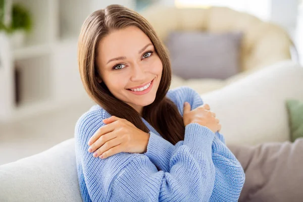 Retrato de menina alegre atraente sentado no divã abraçando-se roupas confortáveis em casa plana luz apartamento interior — Fotografia de Stock