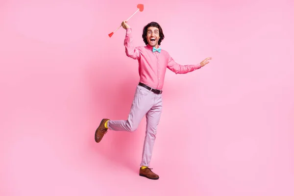 Lunghezza completa foto di allegro dentato bruno capelli uomo tiro mani braccia cupido frecce isolato colore rosa sfondo — Foto Stock