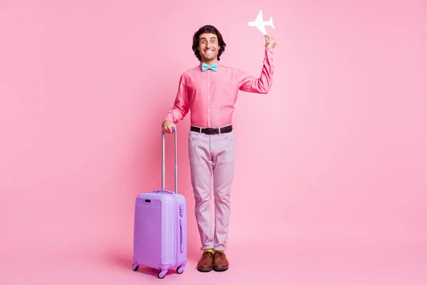 Foto em tamanho completo de bonito morena funky na moda cara segurar papel avião bagagem usar calças roxas óculos isolados no fundo cor-de-rosa — Fotografia de Stock