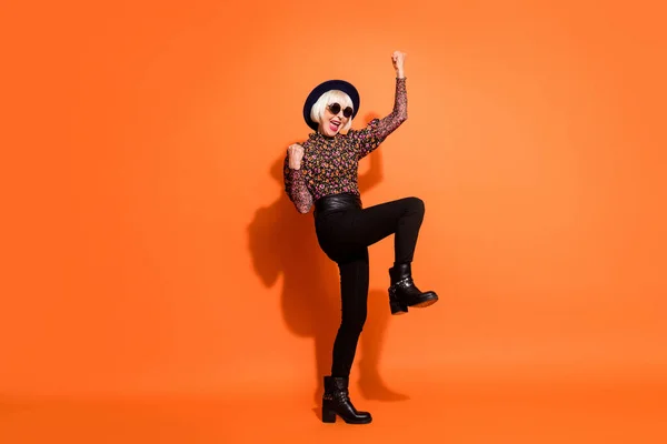 Foto de tamaño completo de la sonriente loca hipster vieja dama levantan los puños en la victoria aislado sobre fondo de color naranja —  Fotos de Stock