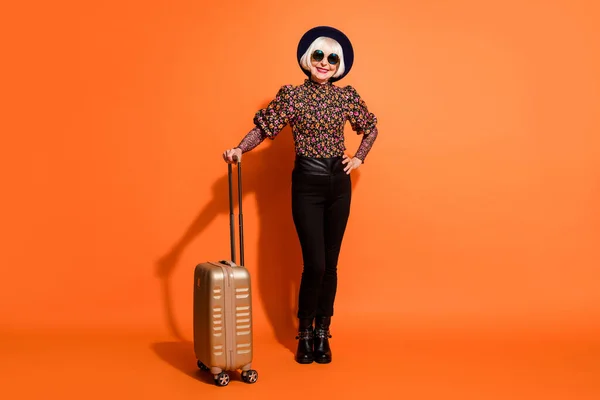 Foto em tamanho completo de sorrindo alegre positivo avó segurar bagagem desgaste calças pretas isoladas no fundo cor de laranja — Fotografia de Stock