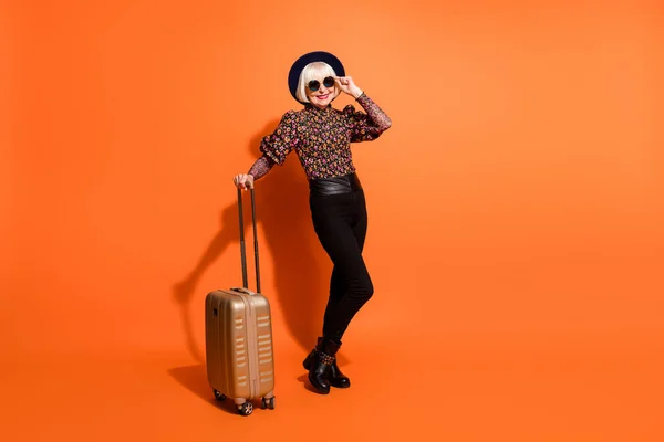 Foto de tamaño completo de edad sonriente alegre buen humor dama equipaje de bodega desgaste pantalones negros aislados sobre fondo de color naranja — Foto de Stock