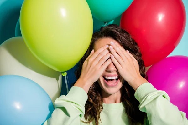 Foto de señora divertida globos detrás de la espalda boca abierta manos palmas cubren los ojos usan jersey verde aislado color azul fondo —  Fotos de Stock