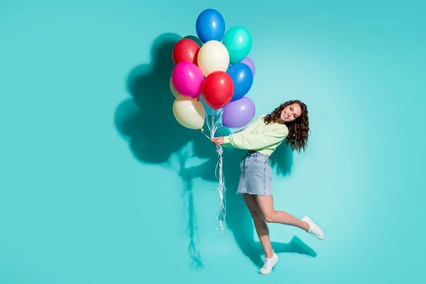 Foto de linda niña sostener muchos globos danza usar zapatillas de deporte verde jersey mini jeans falda aislado color azul fondo — Foto de Stock