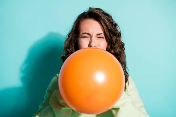 Fotografie legrační roztomilá dáma foukání oranžový balón zavřít oči nosit zelený svetr izolované modré barvy pozadí — Stock fotografie