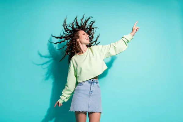 Fényképezés portré fiatal lány barna göndör haj tánc felfelé mutató ujjával elszigetelt élénk kék háttér — Stock Fotó