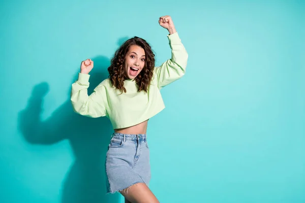 Foto de feliz gritar jovem senhora levantar punhos vestido verde pulôver saia jeans isolado no fundo cor turquesa — Fotografia de Stock