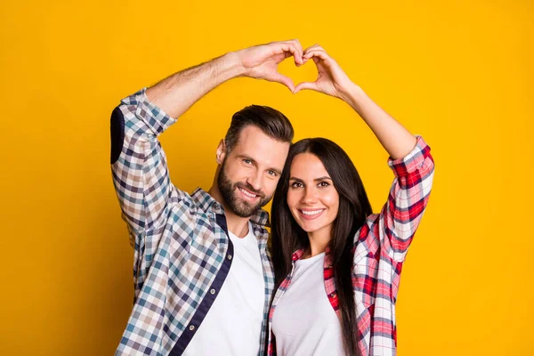 Retrato de casal alegre encantador mostrando a forma do símbolo do coração idílico isolado sobre fundo de cor amarelo brilhante — Fotografia de Stock