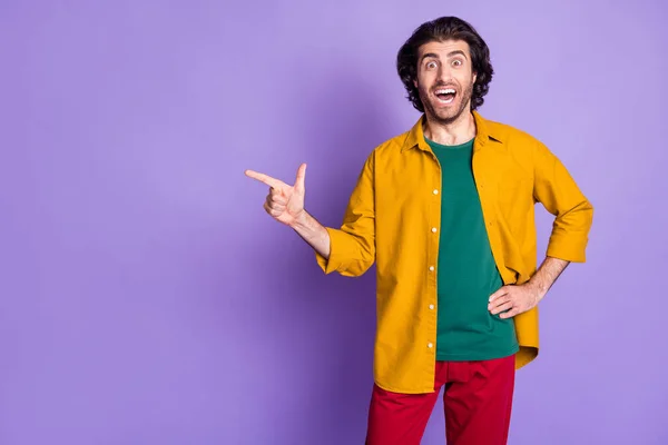 Foto de jovem animado louco homem feliz cara masculino apontando dedo no copyspace isolado no fundo cor violeta — Fotografia de Stock