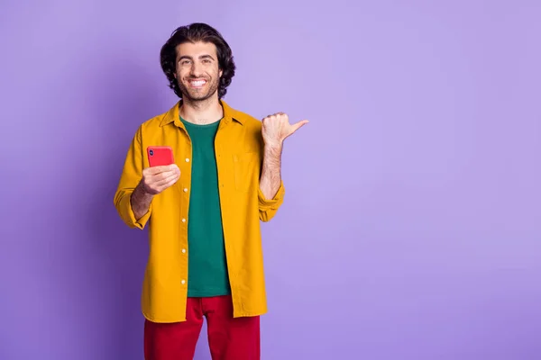 Foto de joven guapo sonriente alegre hombre positivo chico masculino utilizar dedo de la punta del teléfono celular en copyspace aislado sobre fondo de color violeta — Foto de Stock