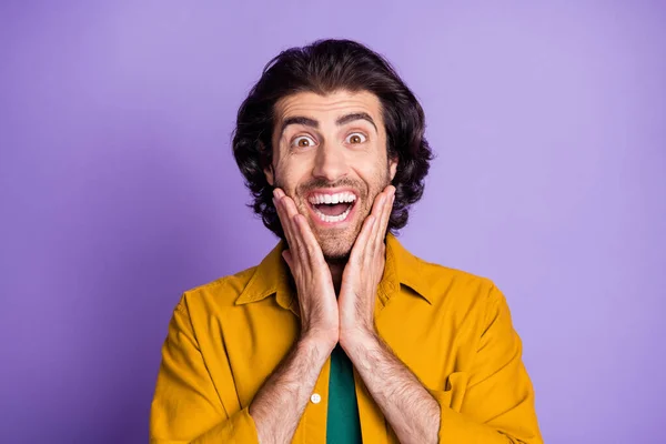 Портрет молодого екстатичного здивованого щасливого шокованого чоловіка хлопця, який кричить тримає руки на щоках ізольовані на фіолетовому кольоровому фоні — стокове фото