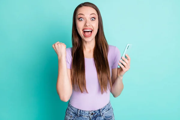 Foto portret van gelukkig verbaasd meisje met smartphone gebaren als winnaar schreeuwen staren geïsoleerd op levendige teal kleur achtergrond — Stockfoto