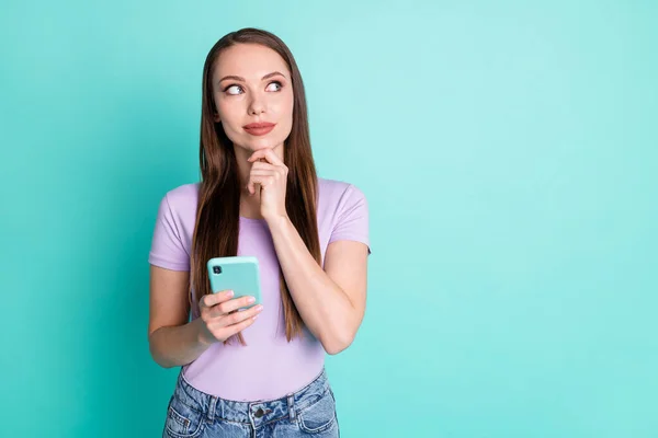 Foto portret van attent meisje met behulp van smartphone aanraken gezicht kijken naar lege ruimte geïsoleerd op levendige teal kleur achtergrond — Stockfoto