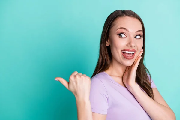 Side profile photo of girl pointing looking at copyspace with thumb smiling touching face isolated on vibrant teal color background — ストック写真