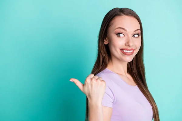 Foto de perfil lateral de la chica apuntando al espacio de copia con el pulgar sonriendo aislado sobre fondo de color verde azulado vivo — Foto de Stock