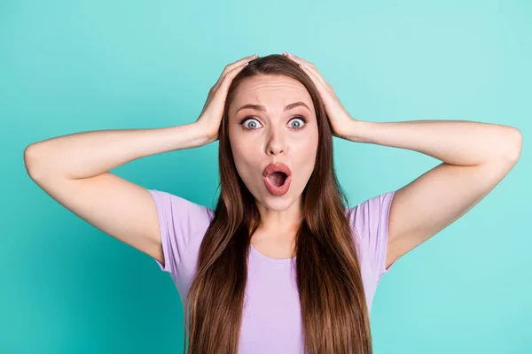 Foto retrato de una mujer con problemas manteniendo la cabeza con las manos mirando con la boca abierta aislada sobre fondo de color verde azulado brillante —  Fotos de Stock