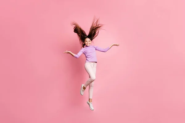 어린 소녀가 점프하는 모습을 찍은 전신 사진은 파스텔 색 배경 위에 따로 떨어져 있는 보라색 스웨터를 입고 있다 — 스톡 사진