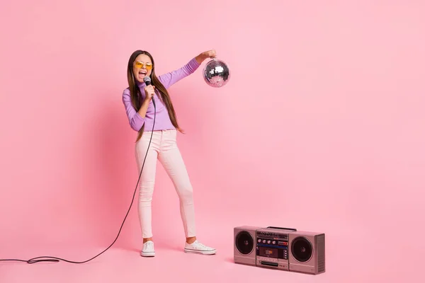 In voller Länge Foto von kleinen Mädchen singen Song Mikrofon halten Discokugel mit Boom-Box isoliert über pastellfarbenen Hintergrund — Stockfoto