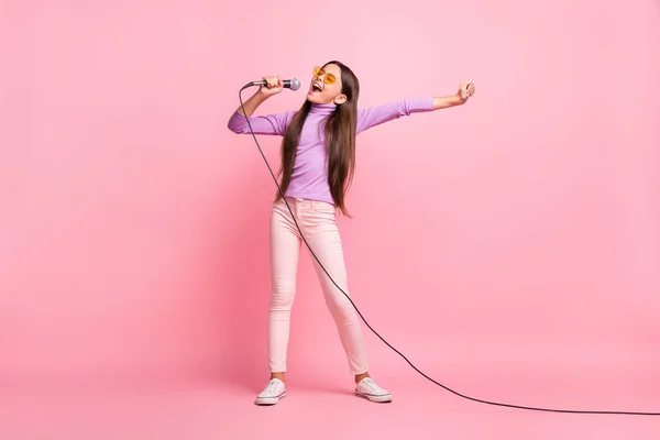 마이크로 노래하는 어린 소녀의 몸 전체 사진 보라색 점퍼 바지를 입고 파스텔 색 배경 위에 격리 — 스톡 사진
