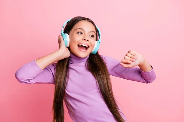 Foto de hipster positivo niña pequeña escuchar lista de reproducción en la danza auriculares inalámbricos aislados sobre fondo de color pastel —  Fotos de Stock