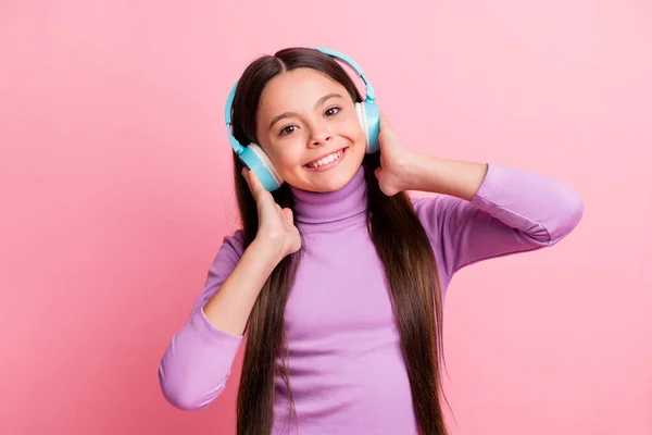 Zdjęcie pozytywne małe dziecko dziewczyna słuchać piosenki na bezprzewodowym słuchawki izolowane na pastelowym tle koloru — Zdjęcie stockowe