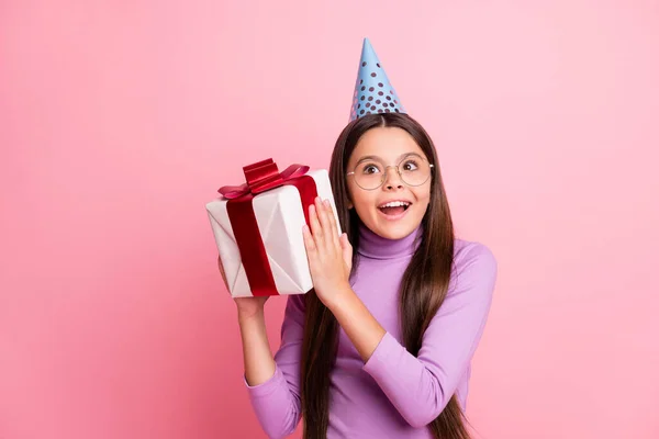 Foto van positief geschokt klein kind meisje schudden gift box slijtage violette verjaardagskap geïsoleerd over pastel kleur achtergrond — Stockfoto