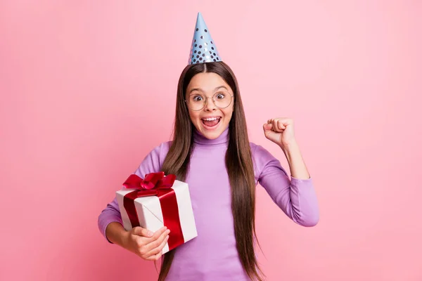 Foto van blij klein meisje houden geschenk doos raise vuisten dragen paarse brithday kegel geïsoleerd op pastel kleur achtergrond — Stockfoto