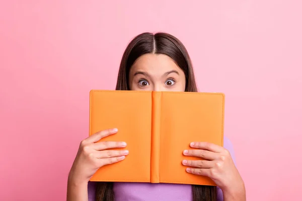 Zdjęcie podekscytowany dzieciak dziewczyna ukryć usta z książki nosić fioletowy sweter izolowane na pastelowym tle koloru — Zdjęcie stockowe