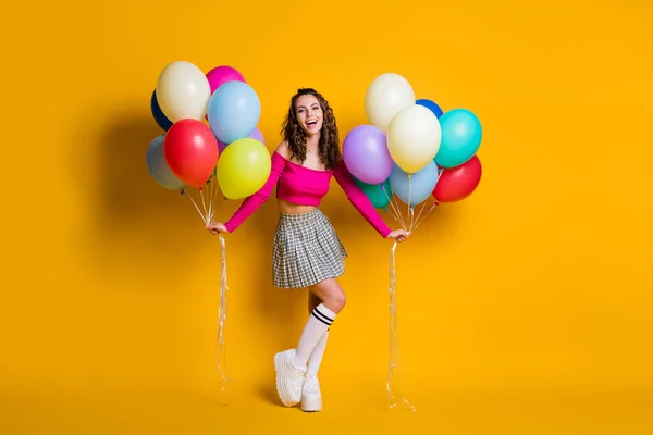 Full length body size photo of pretty female student holding air balloons χαμογελώντας χαρούμενα φορώντας καρό φούστα απομονωμένη σε έντονο κίτρινο χρώμα φόντο — Φωτογραφία Αρχείου