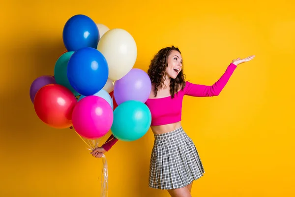 Portret zdjęcie szczęśliwej studentki trzymającej balony z powietrzem uśmiechając się trzymając rękę odizolowaną na jasnożółtym tle — Zdjęcie stockowe
