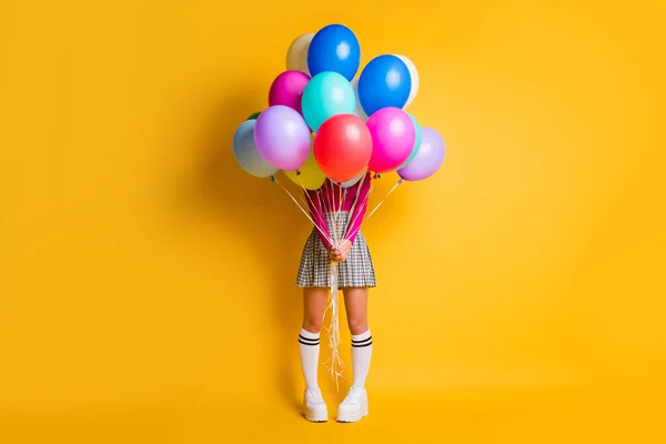 Foto de retrato de una joven estudiante engañando a la cara oculta debajo de la colorida cantidad de globos de aire de pie aislados en el fondo de color amarillo — Foto de Stock