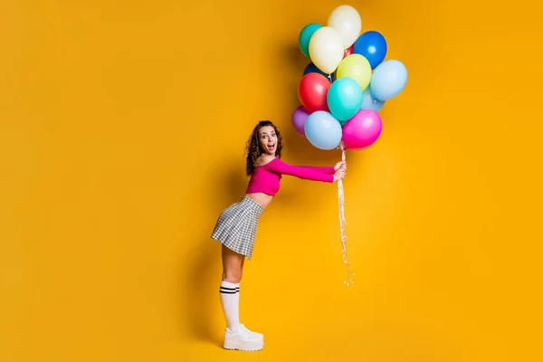 Foto de tamaño completo del cuerpo de una colegiala bastante linda sosteniendo globos de aire sonriendo sorprendida aislada sobre fondo de color amarillo brillante — Foto de Stock
