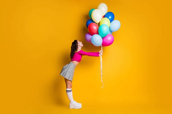 Фотографія повного розміру тіла красивого студента, який тримає повітряні кульки посміхаючись, дивлячись вгору щасливо ізольовано на яскравому жовтому кольорі — стокове фото