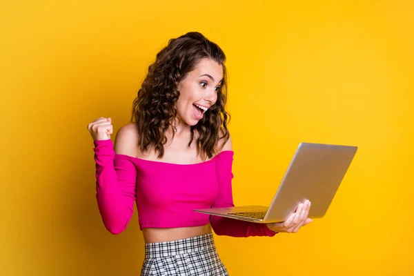 写真の女性ホールドネットブック陽気な驚き運興奮オープン口を上げる拳見て画面を着用ピンクトップの服を着て肩スカート隔離された黄色の色の背景 — ストック写真