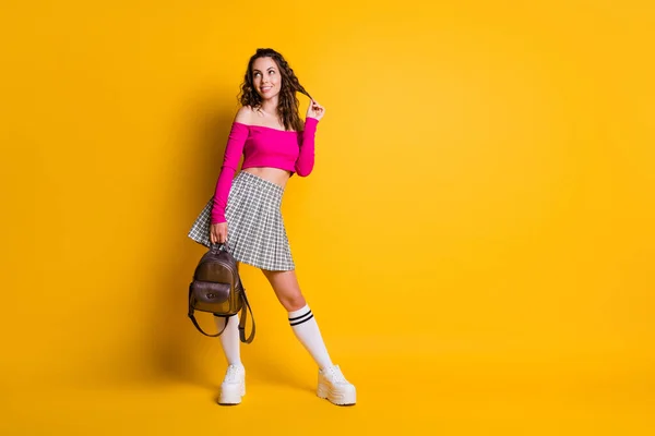 Full längd foto av dam slå upp tomt utrymme håll ryggsäck spela curl bära rosa topp avtäckt axlar mini kjol strumpor sneakers isolerad gul färg bakgrund — Stockfoto