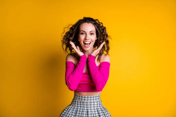 Photo portrait of excited woman holding hands near face smiling wearing pink crop-top checkered skirt isolated on vivid yellow colored background — Stock Photo, Image