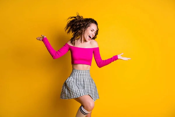 Retrato fotográfico de una mujer despreocupada de pie sobre una pierna manos a los lados con calcetines largos de mini falda a cuadros de top rosa aislados sobre un fondo de color amarillo vivo — Foto de Stock