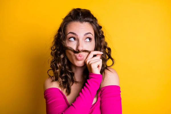 Φωτογραφία πορτρέτο της ονειρική μελαχρινή γυναίκα με παχουλά χείλη κάνοντας ψεύτικο μουστάκι μαλλιά εκμετάλλευση με το ένα χέρι φορώντας casual ροζ καλλιέργεια-top απομονωμένο φωτεινό κίτρινο χρώμα φόντο — Φωτογραφία Αρχείου