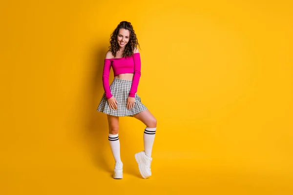 Foto em tamanho completo de menina encantador lindo agradável coquete encaracolado senhora desgaste rosa cortado topo curto xadrez saia branca meias compridas calçado isolado brilho amarelo cor fundo — Fotografia de Stock