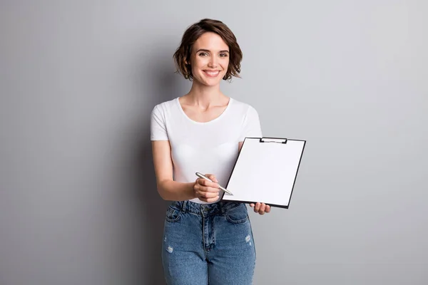 Foto de la joven empresaria sujetar portapapeles mostrar punto pluma firmar contrato aislado sobre fondo de color gris —  Fotos de Stock