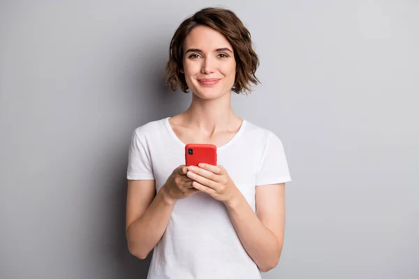 Foto de joven sonrisa alegre blogger chica mantenga teléfono inteligente tipo de chat navegar aislado sobre fondo de color gris —  Fotos de Stock