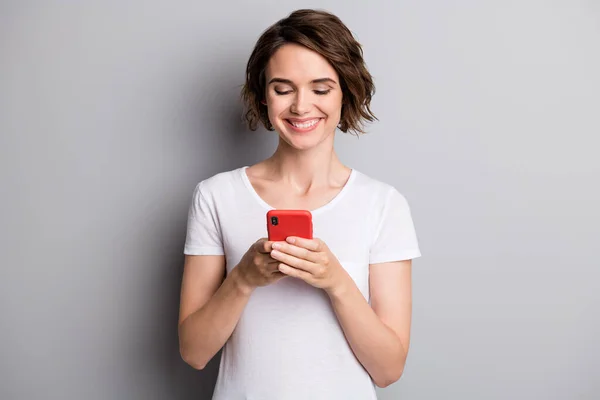 Foto de la joven sonrisa positiva feliz chica celebrar el chat del teléfono celular comunicar post aislado sobre fondo de color gris — Foto de Stock