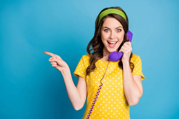 Foto retrato de morena encaracolada falando no telefone violeta apontando dedo no copyspace isolado no fundo de cor azul claro pastel — Fotografia de Stock