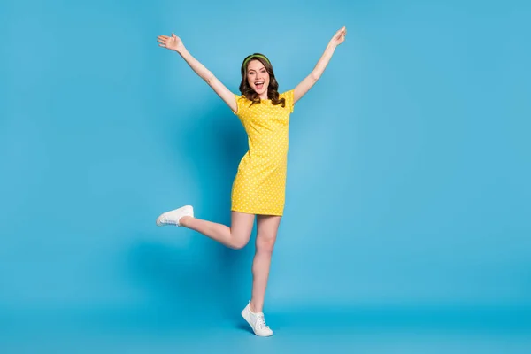 Full kropp foto av flickaktig entusiastisk ung flicka lyfta händerna benet isolerad över blå färg bakgrund — Stockfoto