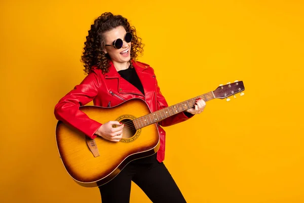 Portret van vrij vrolijke getalenteerde beroemde golvende harige meisje spelen gitaar geïsoleerd op fel gele kleur achtergrond — Stockfoto
