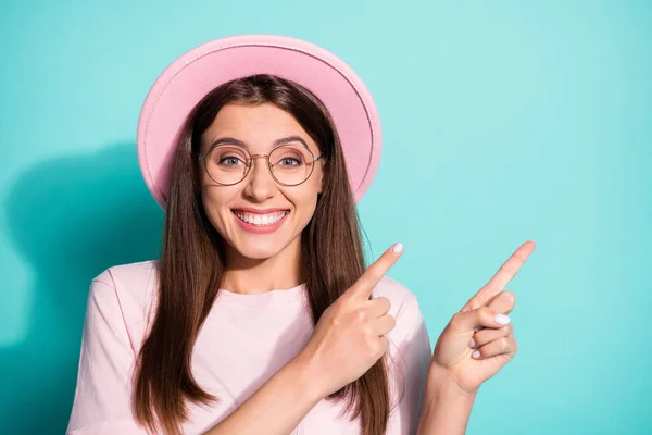 Foto de toothy chica estudiante difícil vestido rosa gorra de la camiseta señalando espacio vacío dos dedos aislados color turquesa fondo — Foto de Stock