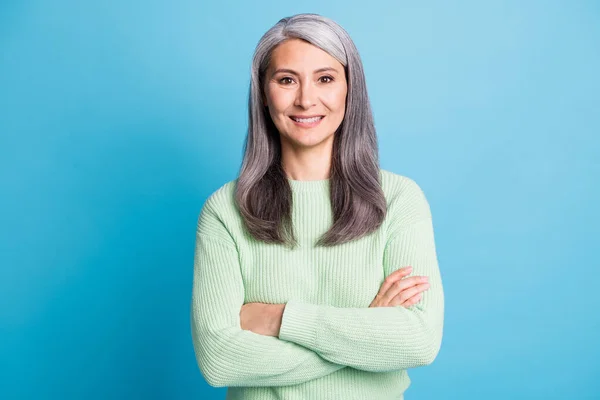 Фото пожилой женщины в отставке сложенные руки блестящие белые улыбающиеся носить зеленый свитер изолированный синий цвет фона — стоковое фото