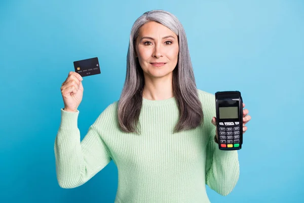 Foto della nonna in pensione tenere carta di debito terminale sguardo fotocamera sorriso usura verde pullover isolato colore blu sfondo — Foto Stock