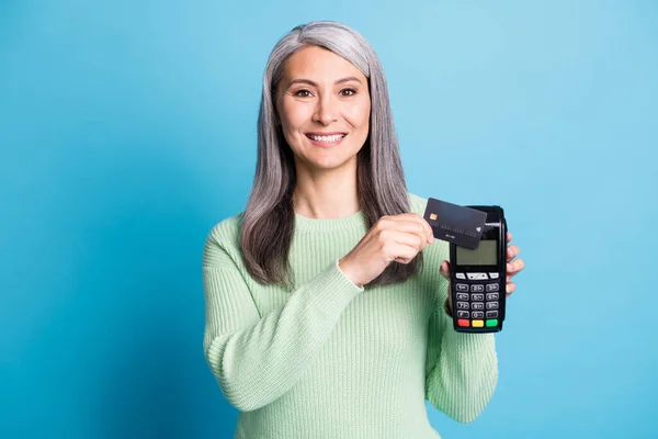Foto di positivo signora matura dimostrare carta di credito pos terminale usura maglione verde isolato su sfondo di colore blu — Foto Stock
