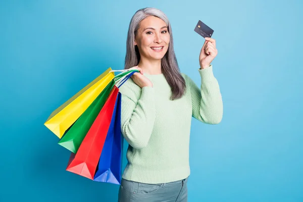 Photo of nice retired woman carry packages demonstrate credit card dressed casual wear isolated on blue color background — Stock Photo, Image